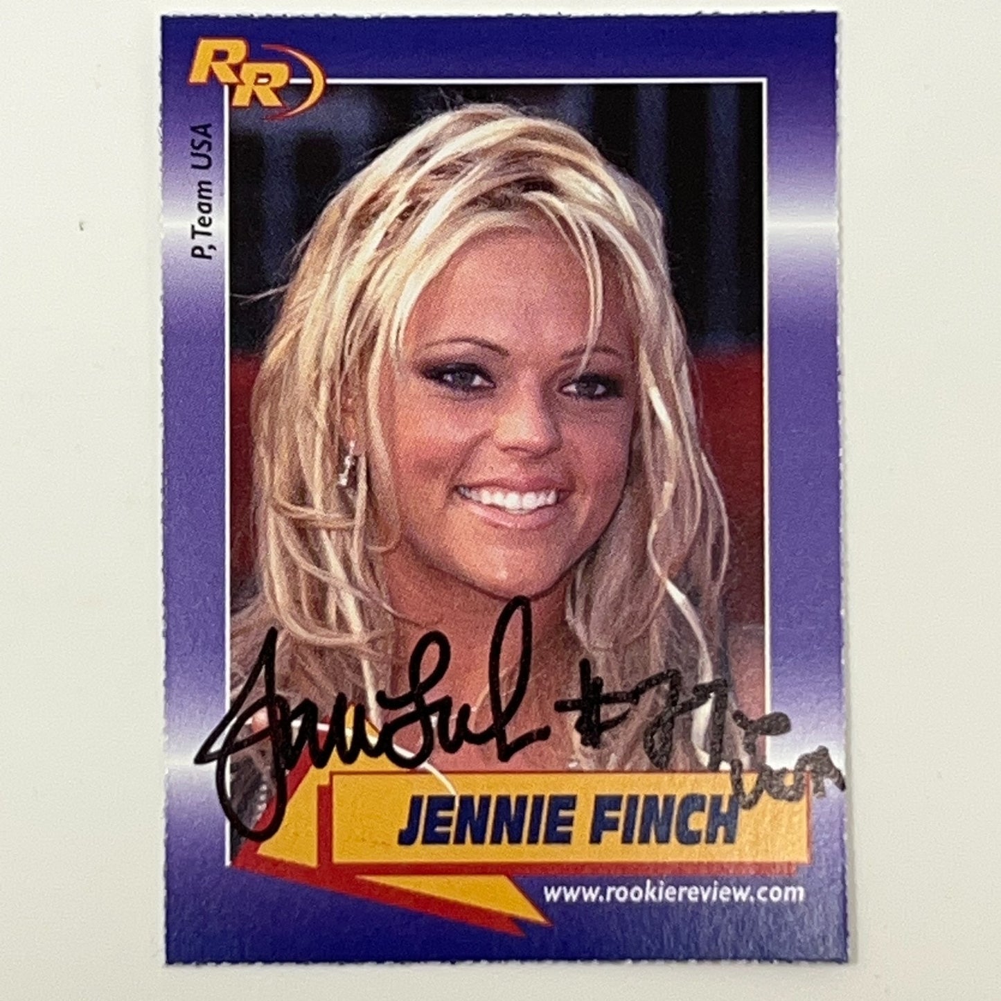 Signed Jennie Finch trading card featuring her portrait with blonde hair and autograph on purple background
