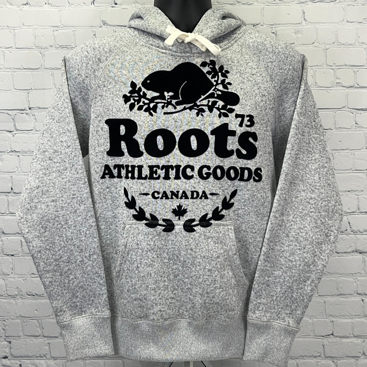 Front view of gray Roots hoodie featuring bold logo, beaver design, and drawstring hood