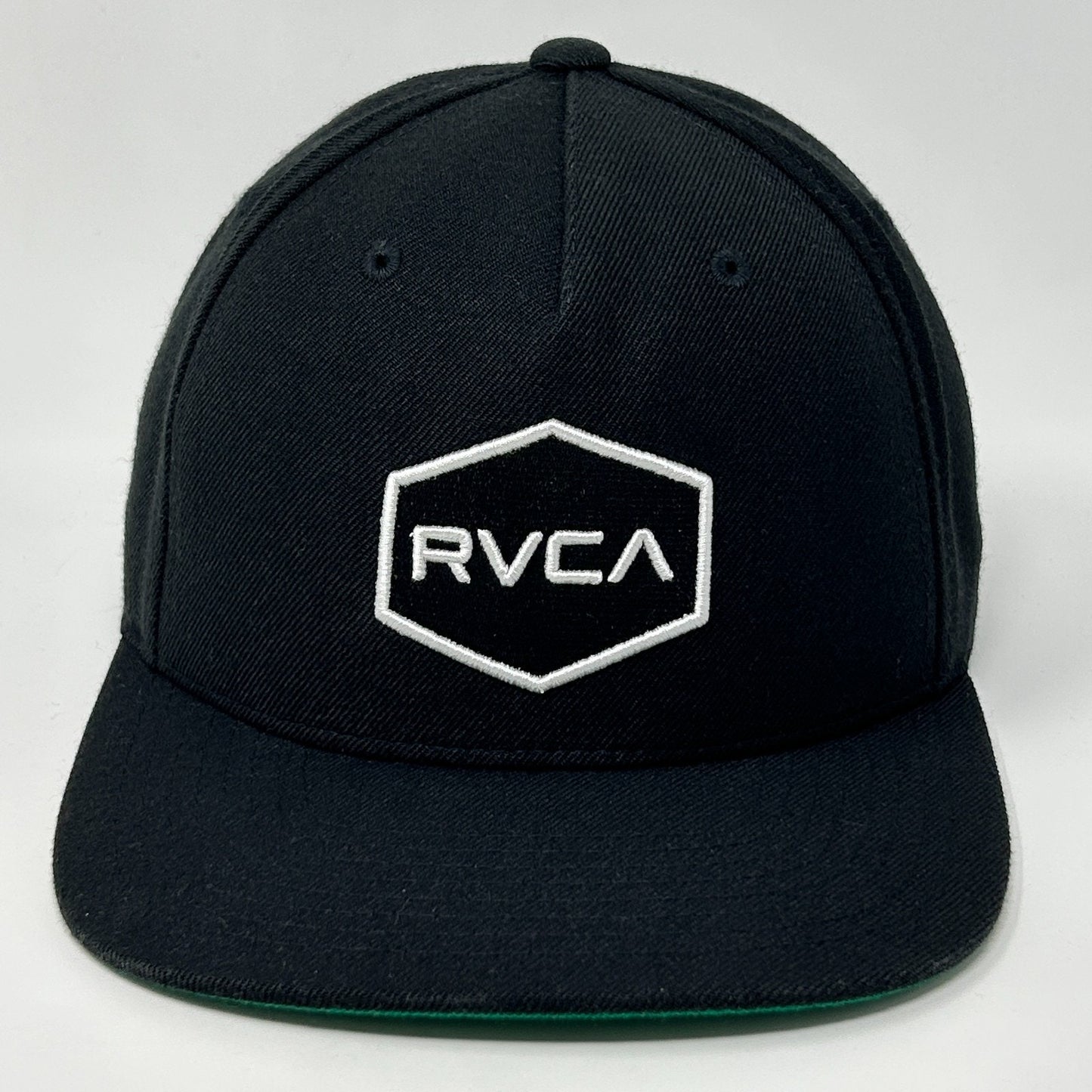 Front view of RVCA black snapback hat with white logo and hexagon design