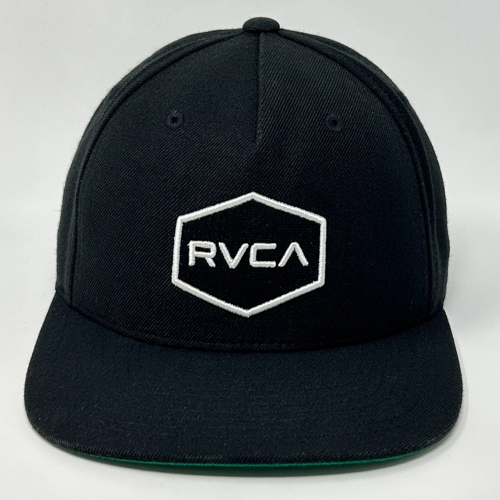 Front view of RVCA black snapback hat with white logo and hexagon design