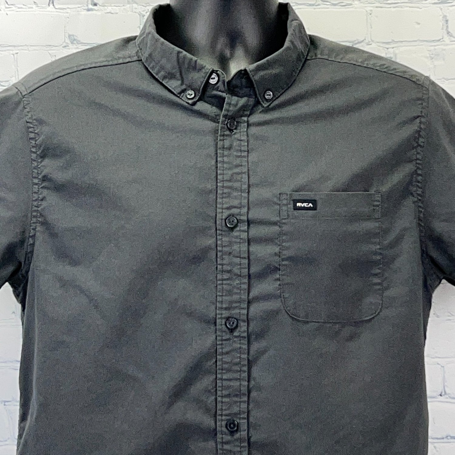 Front view of a dark gray RVCA shirt with a button-up design and a front pocket logo