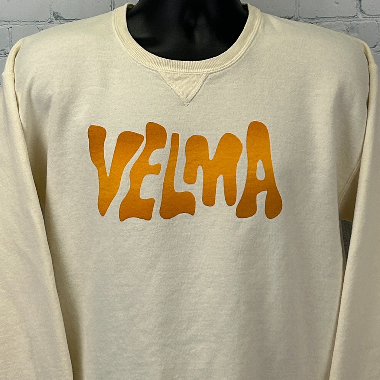 Cream Scooby Doo Sweatshirt featuring a bold orange 'VELMA' graphic on the front