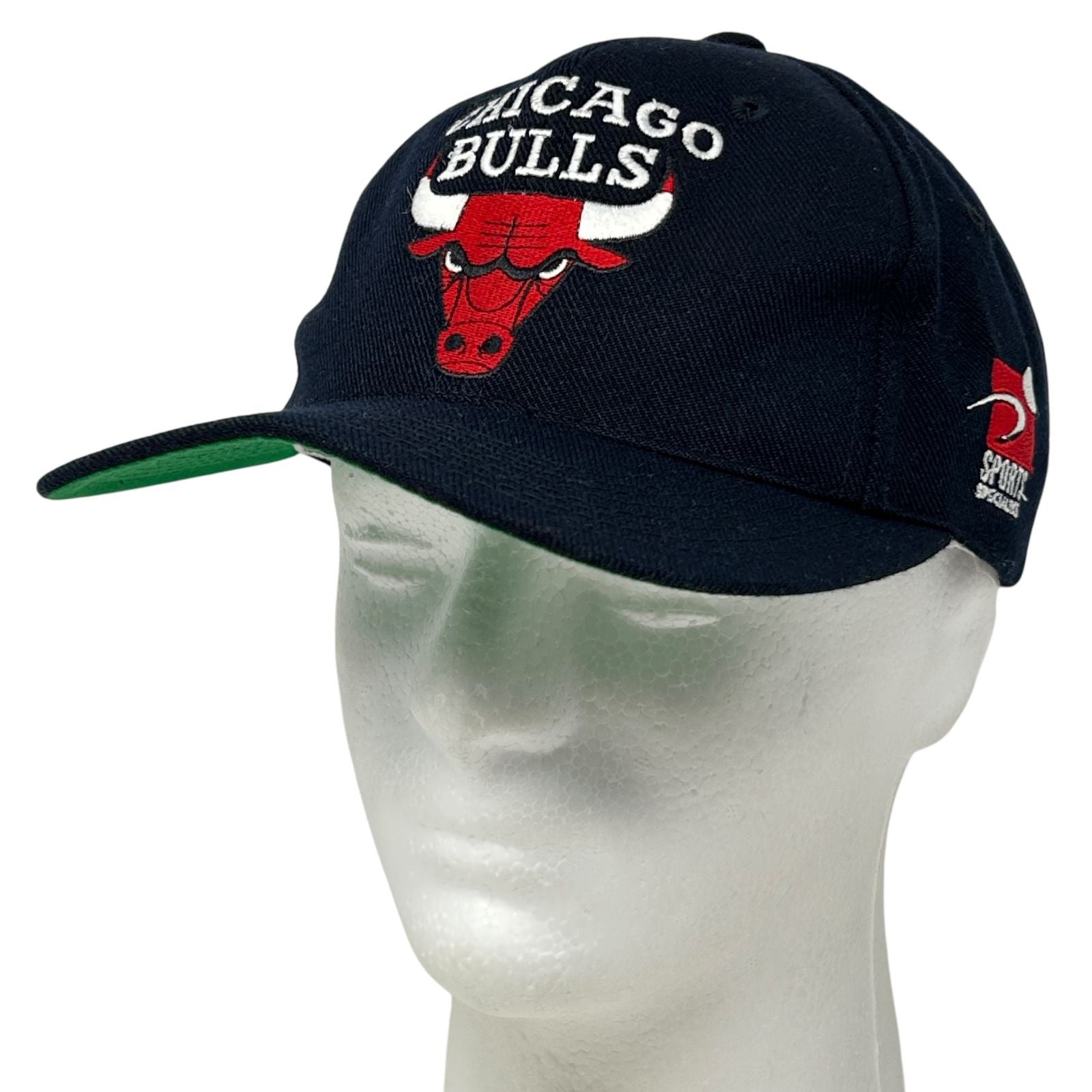 Front view of a black Chicago Bulls hat with embroidered logo and green brim
