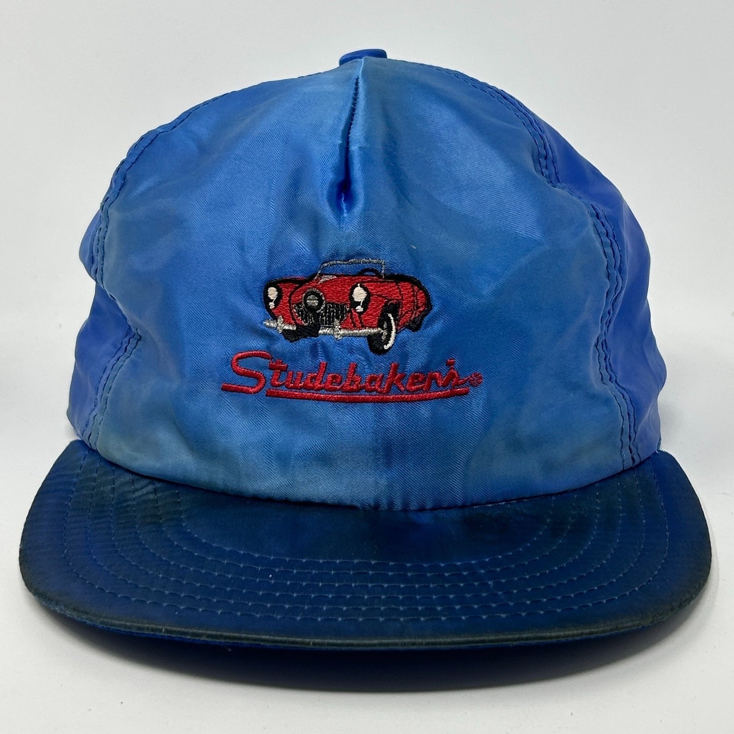 Front view of a blue Vintage Hat featuring embroidered Studebaker logo and classic car design