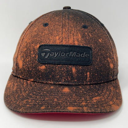 Front view of TaylorMade baseball cap hat in orange and black with logo and distressed finish
