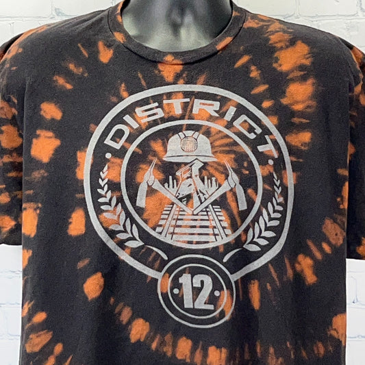 The Hunger Games T Shirt in black and orange tie-dye with District 12 logo on the front