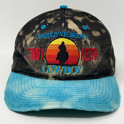 Distressed black and blue Toby Keith cowboy hat with colorful sunset embroidery on the front