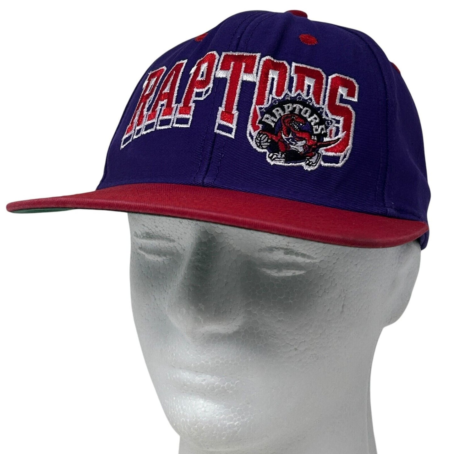 Front view of purple adidas Toronto Raptors snapback hat with embroidered logo and red brim
