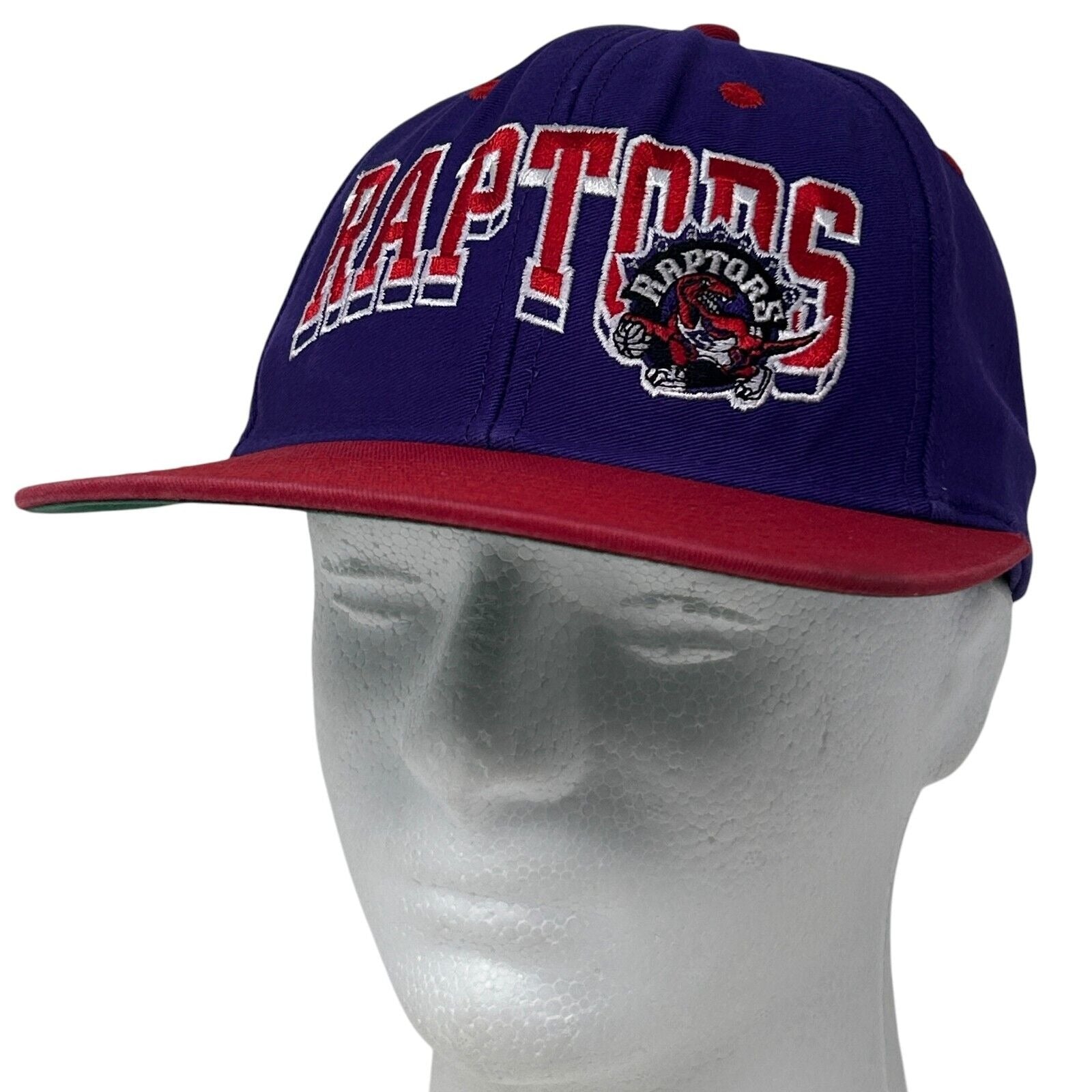 Front view of purple adidas Toronto Raptors snapback hat with embroidered logo and red brim