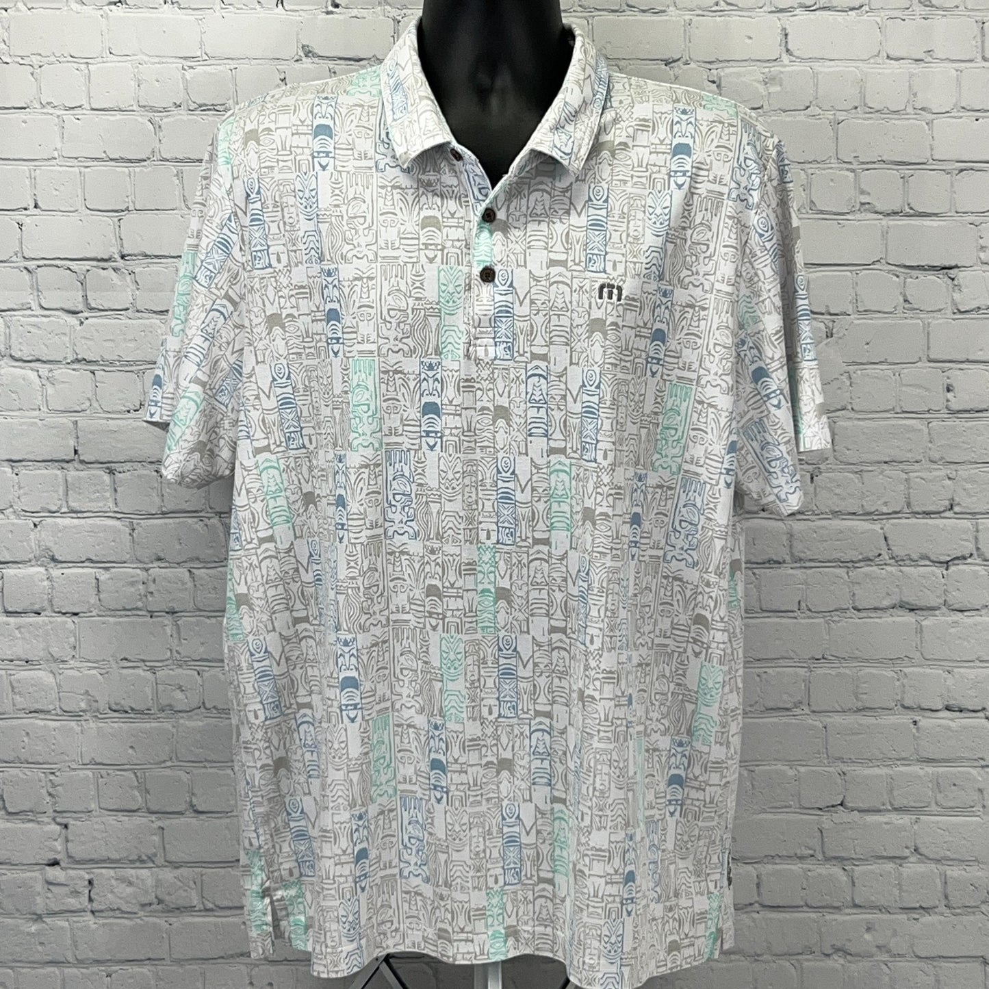 Travis Mathew short-sleeve polo shirt in white with a colorful geometric pattern, featuring logo on chest
