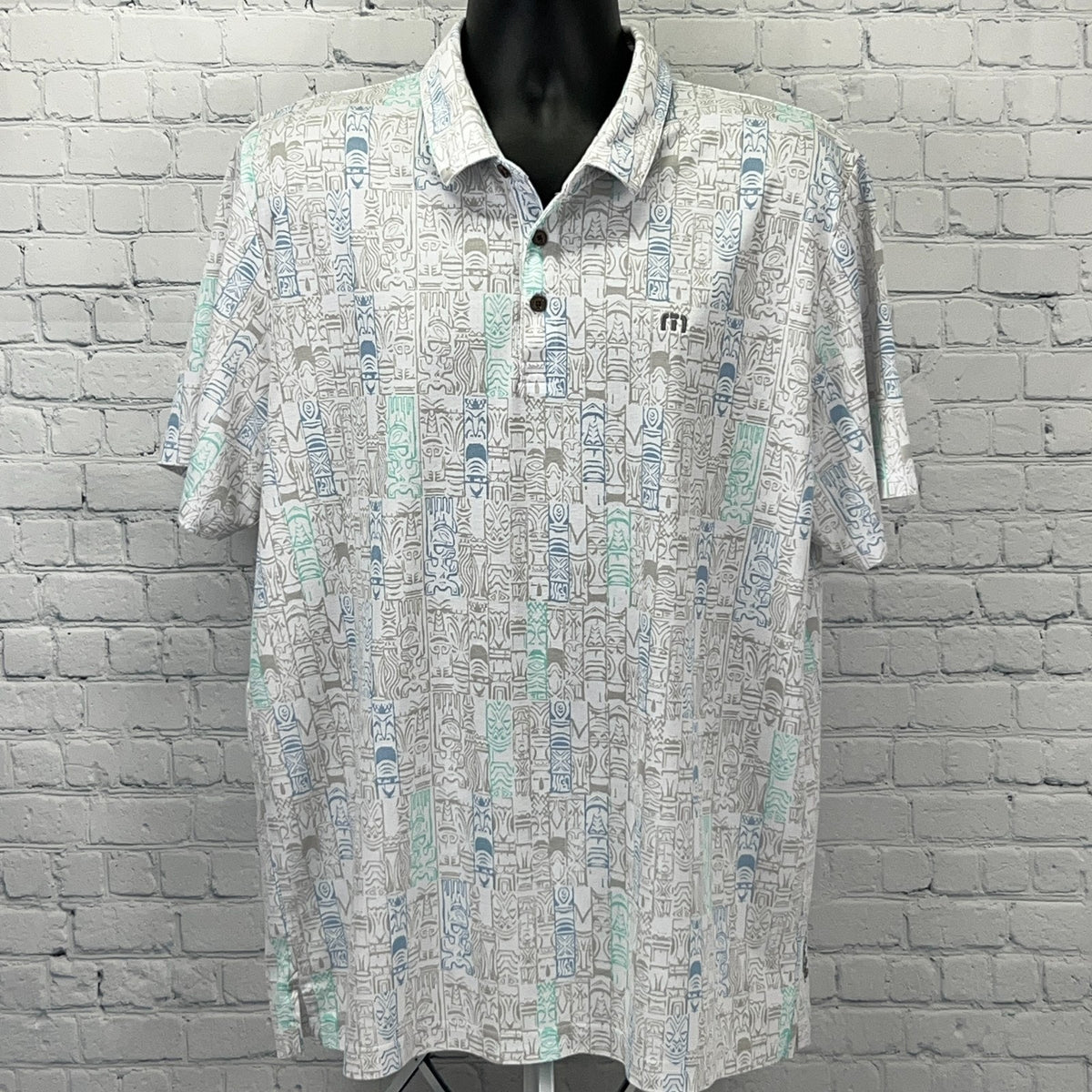Travis Mathew short-sleeve polo shirt in white with a colorful geometric pattern, featuring logo on chest