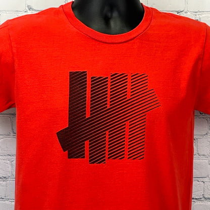 Undefeated T Shirt in red featuring black striped logo on the front for a bold look