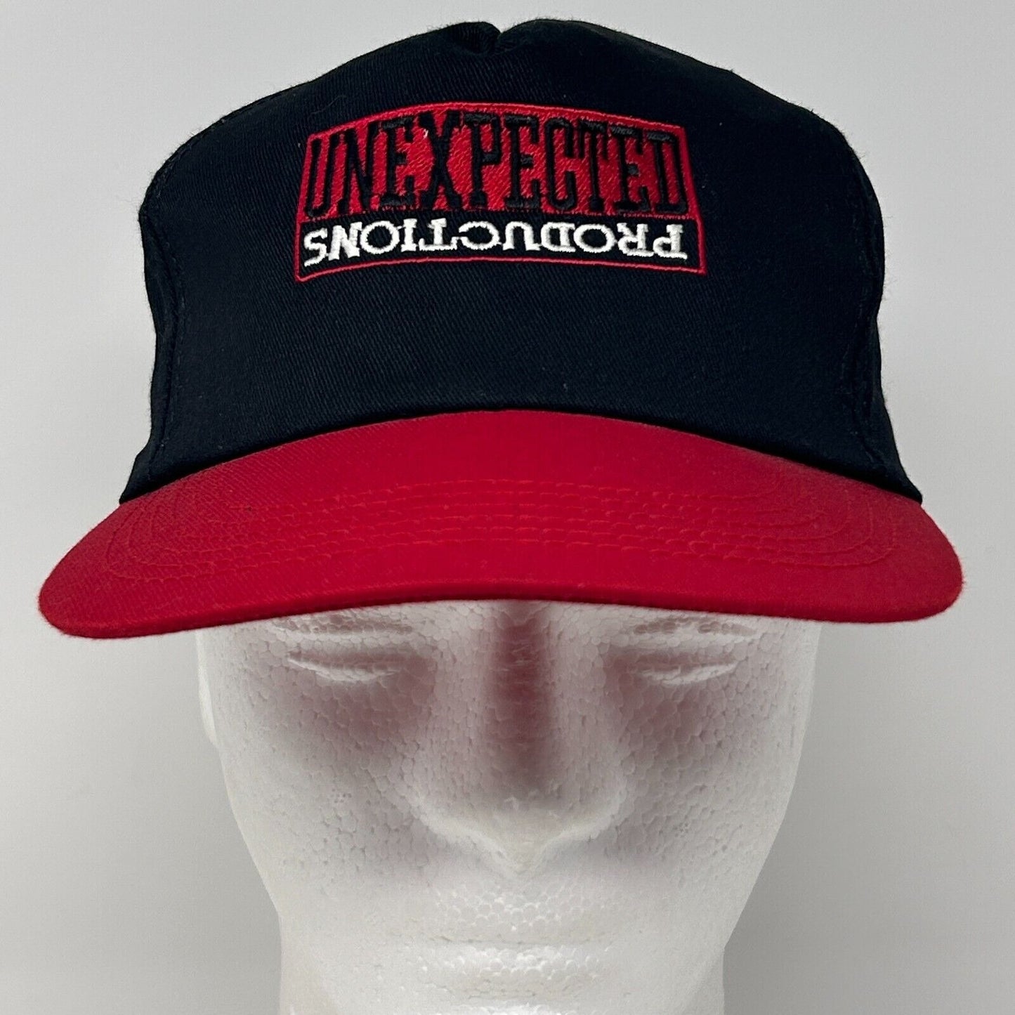 Front view of black and red Vintage hat with Unexpected Productions logo embroidered on the front