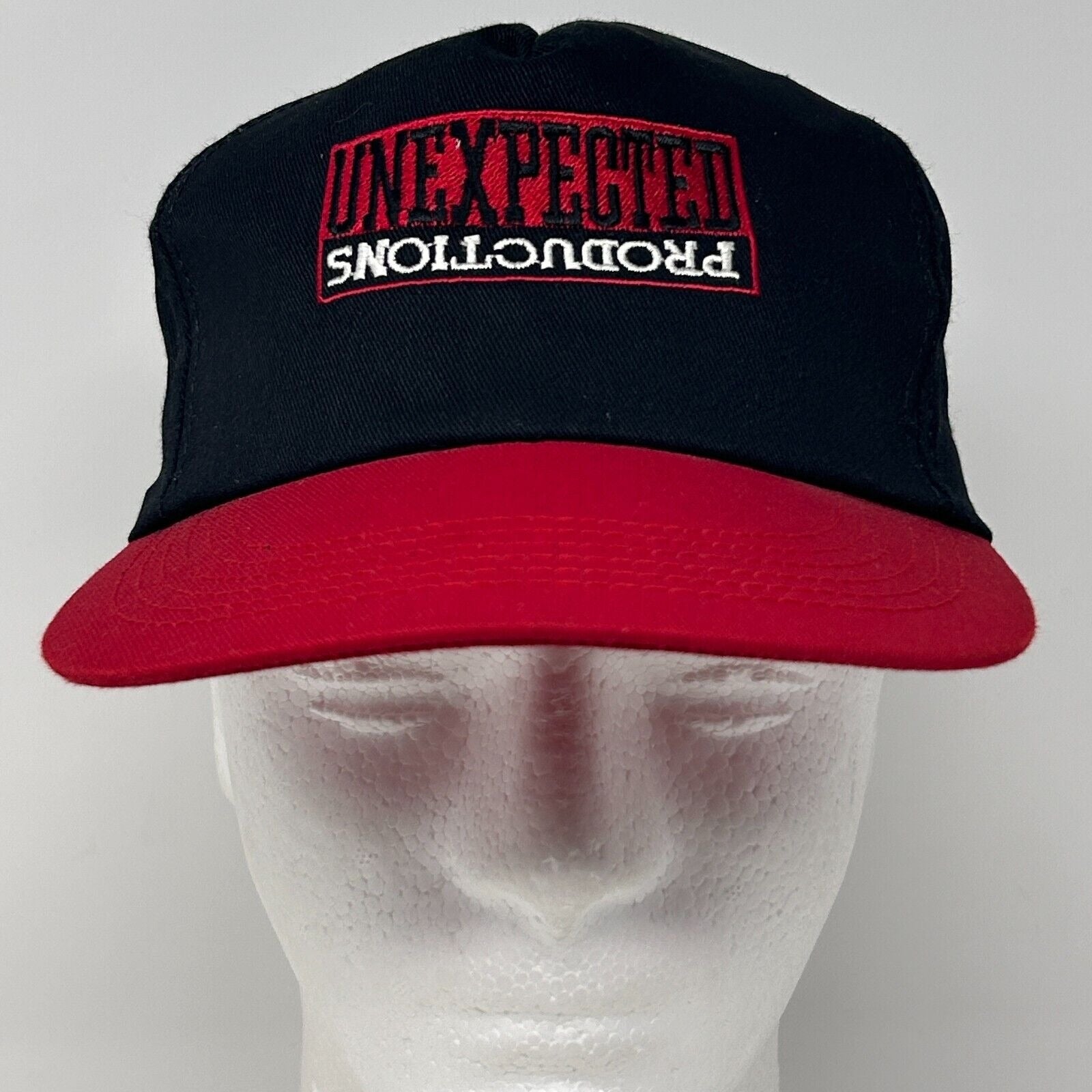 Front view of black and red Vintage hat with Unexpected Productions logo embroidered on the front