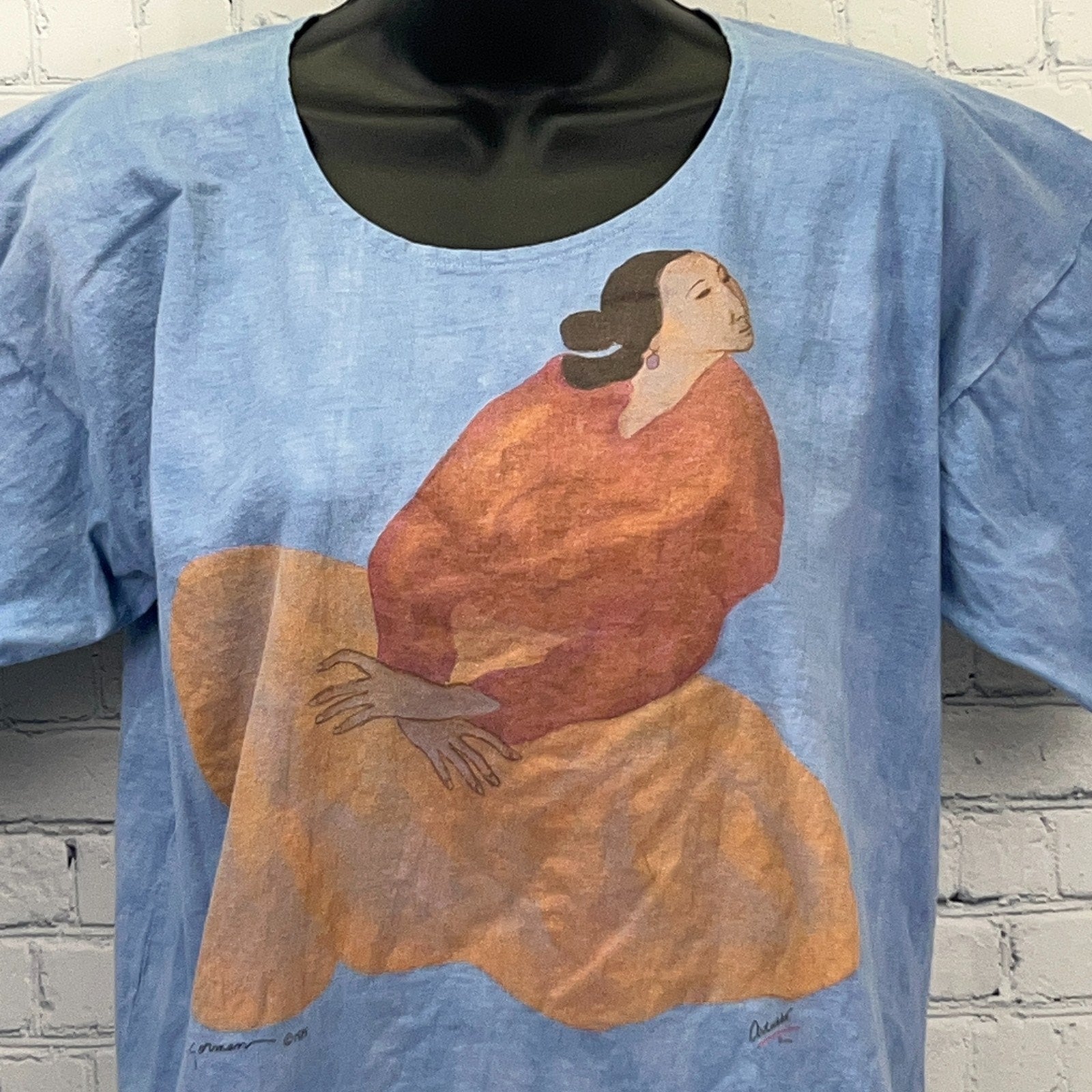 Vintage Native American graphic t-shirt featuring a colorful woman in a red dress on a light blue background