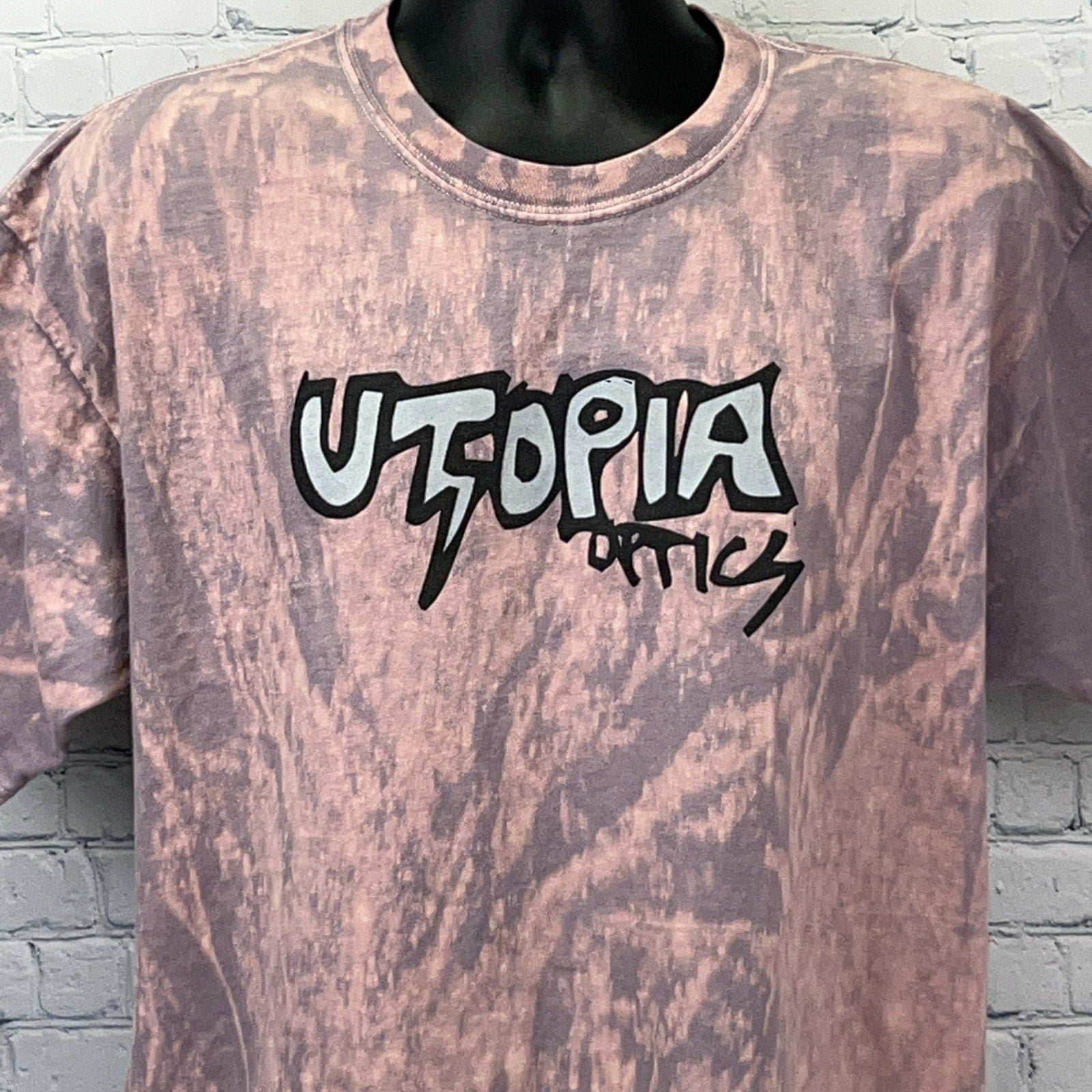 Front view of pink vintage t-shirt featuring Utopia Optics logo in stylized design