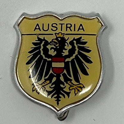 Vintage Austrian coat of arms pin with a black eagle and gold background, featuring the word Austria