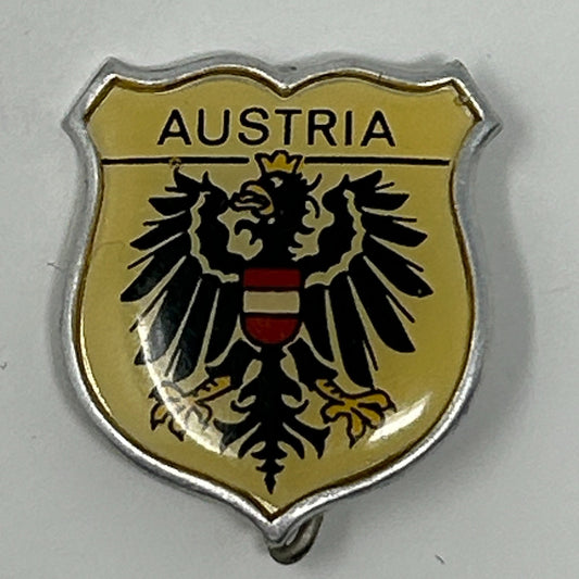 Vintage Austrian coat of arms pin with a black eagle and gold background, featuring the word Austria