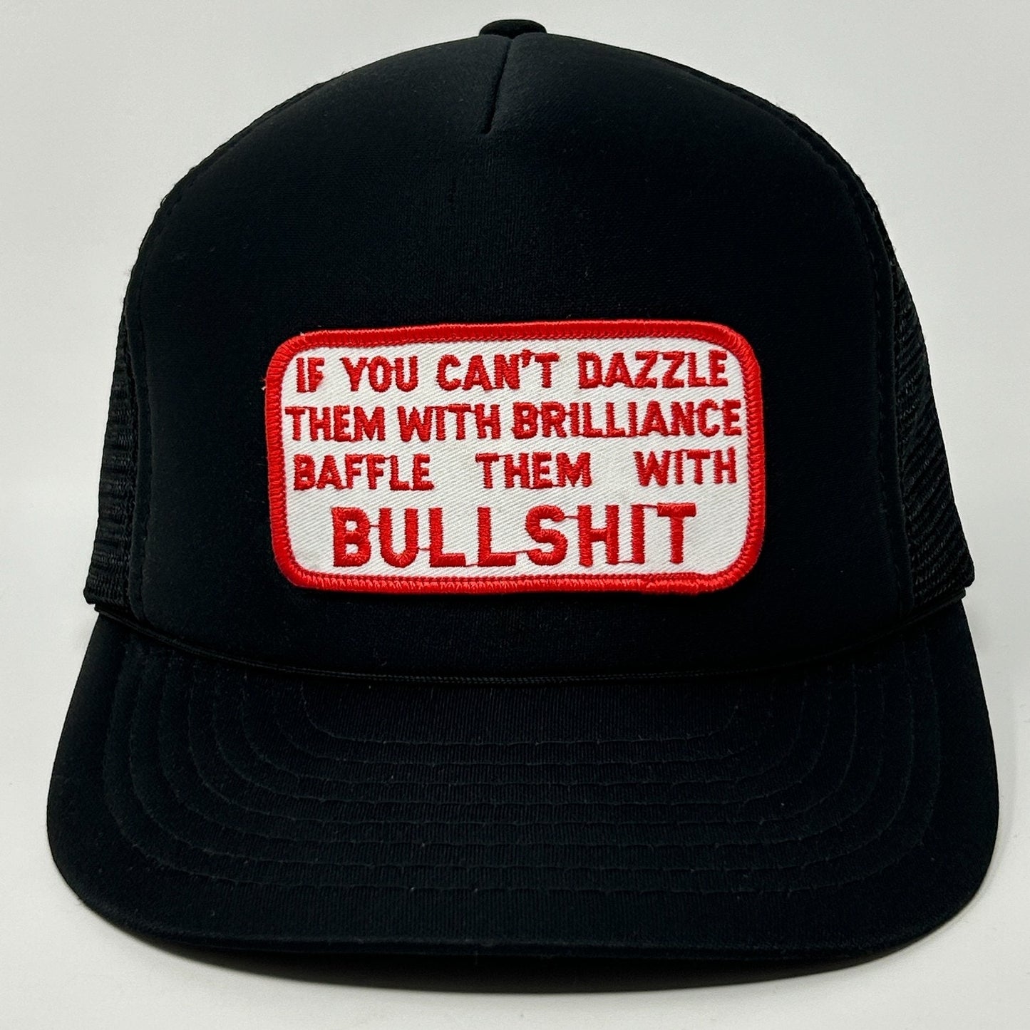 Black Vintage Trucker Hat with a bold red and white patch saying 'If you can't dazzle them with brilliance baffle them with bullshit'