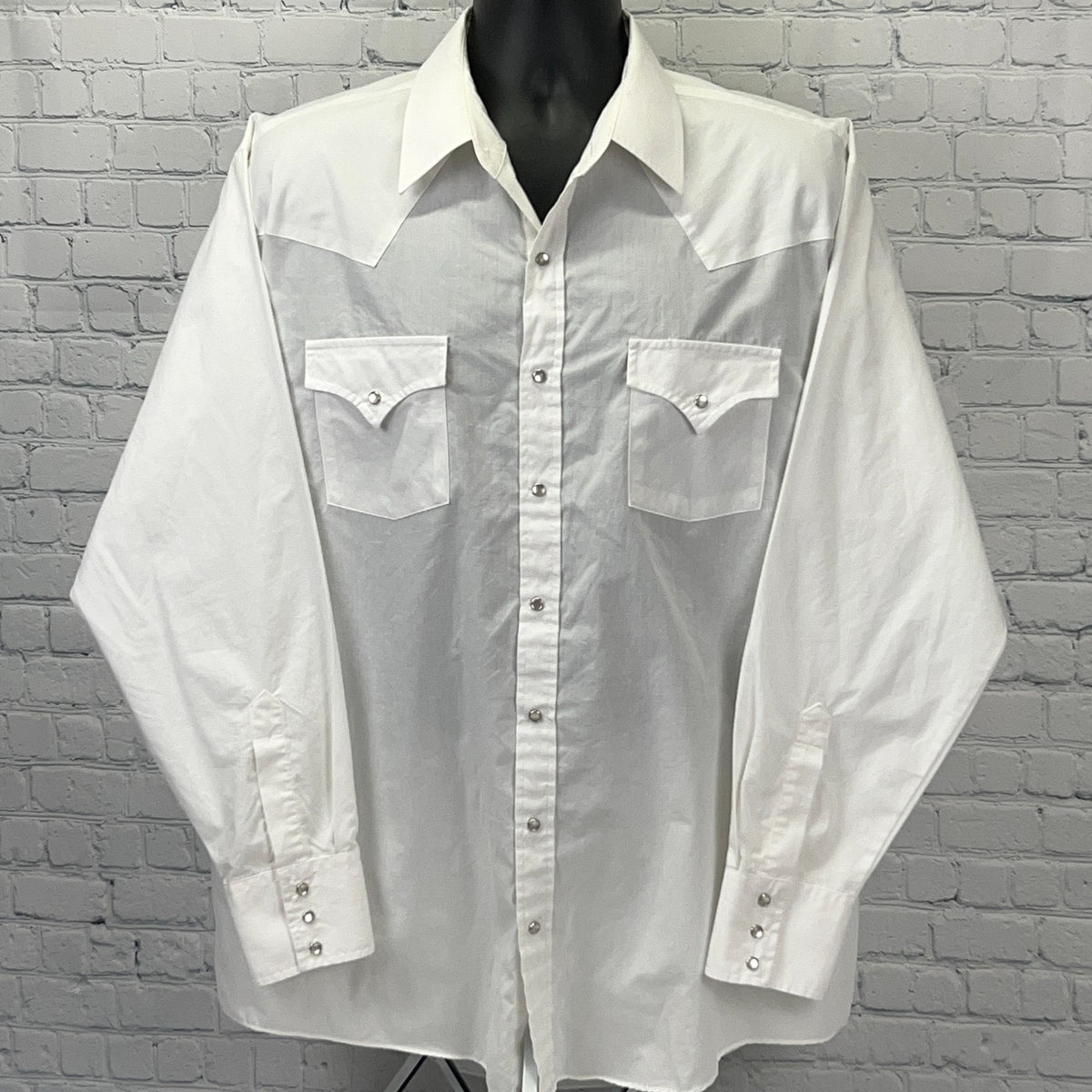 White Western shirt with long sleeves, snap buttons, and front pockets for a classic look