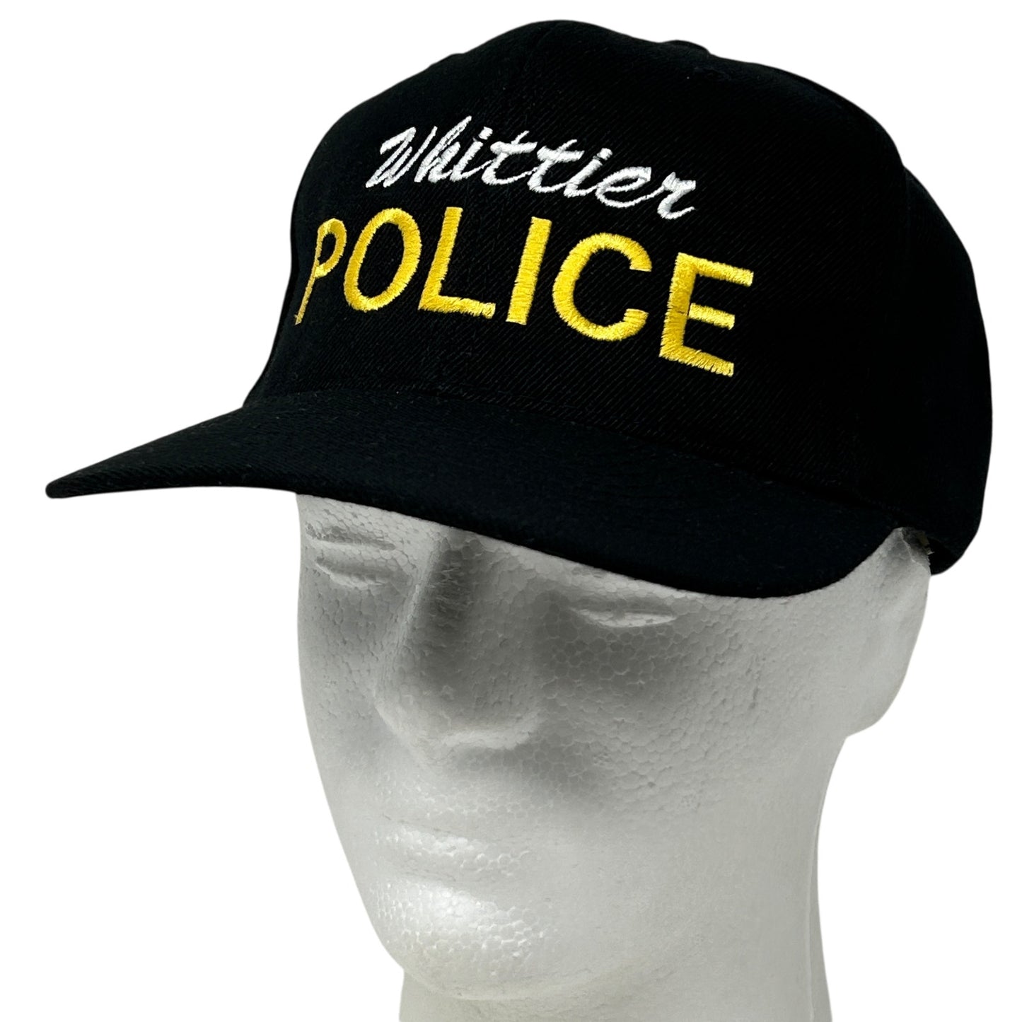 Black baseball cap featuring 'Whittier Police' embroidered in white and yellow on the front