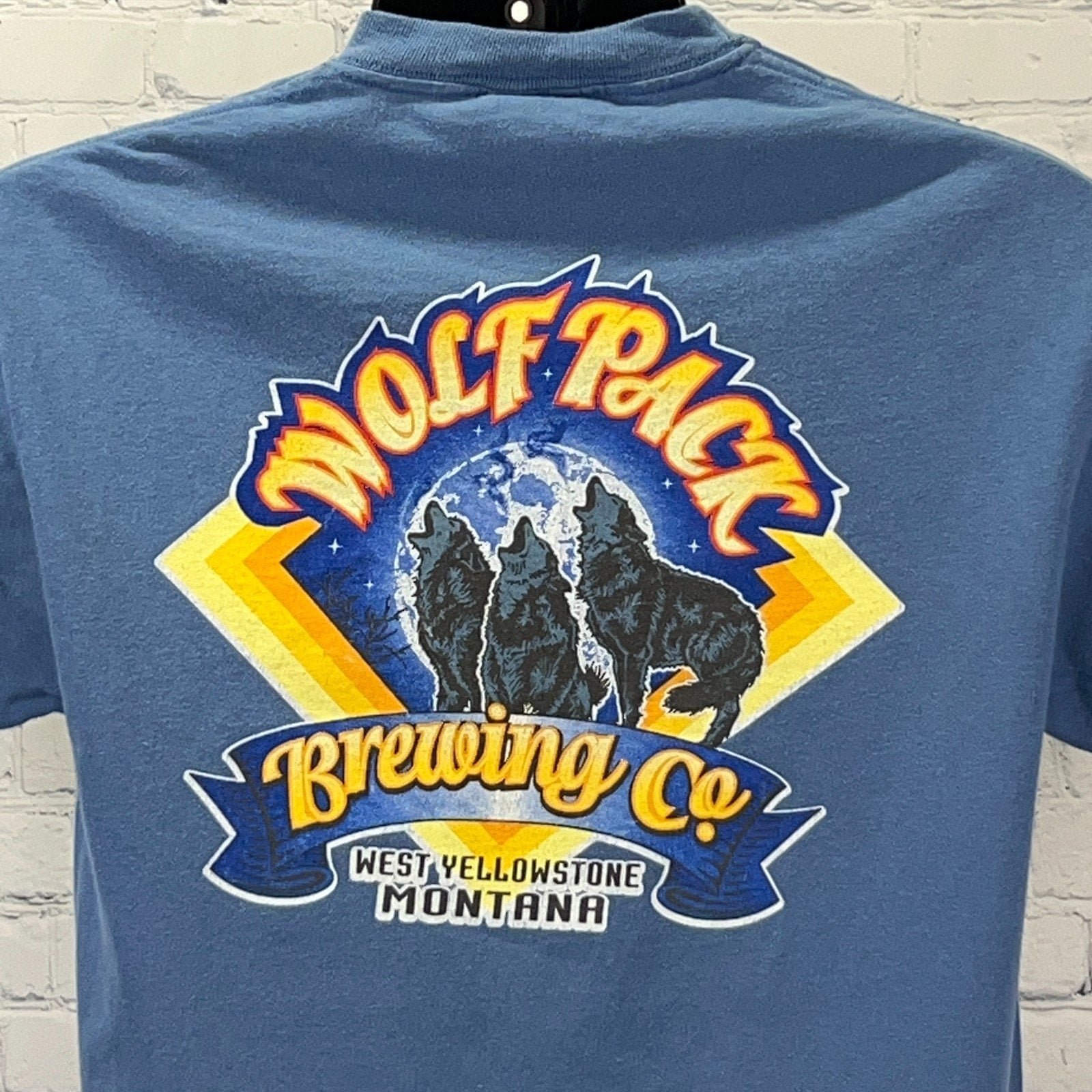 Back view of blue Hanes t-shirt featuring Wolf Pack Brewing Co logo and Yellowstone graphics